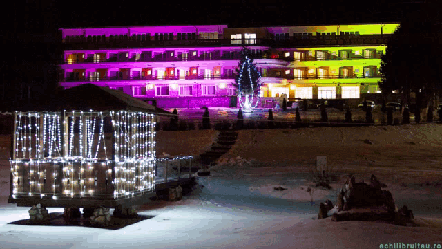 a gazebo is lit up in front of a large building