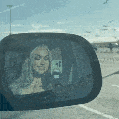 a woman is taking a picture of herself in a car mirror