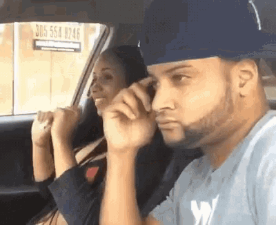 a man and woman are sitting in the back seat of a car .