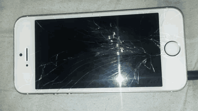 a phone with a cracked screen and a smiley face on the screen