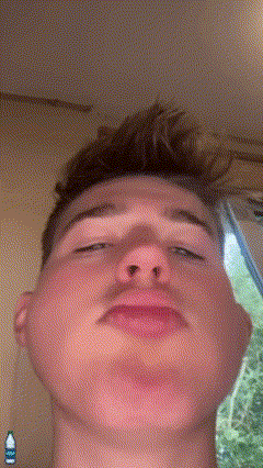 a close up of a young man 's face with a bottle of water behind him