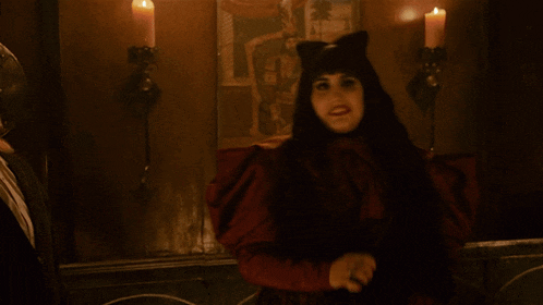 a woman in a cat costume is holding a knife in a dark room