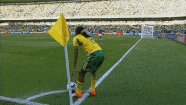 a soccer player in a yellow jersey stands on the corner of the field