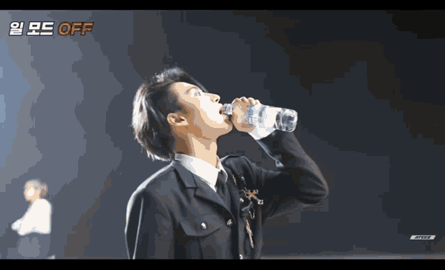 a man in a suit drinking water from a bottle with the word off on the bottom