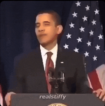 a man in a suit and tie stands at a podium that says realstiffy on it