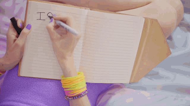 a woman is writing in a notebook that says is