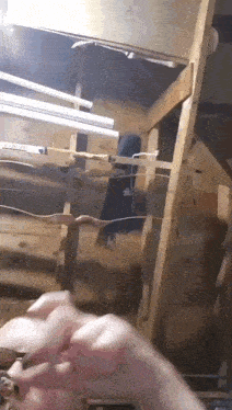 a person 's hands are reaching up towards a wooden shelf with a light hanging from it .