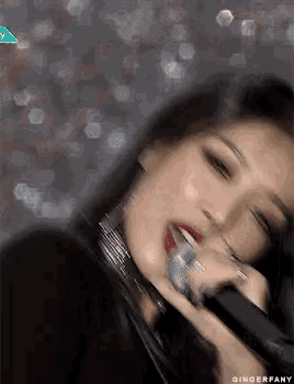a close up of a woman holding a microphone in her mouth .