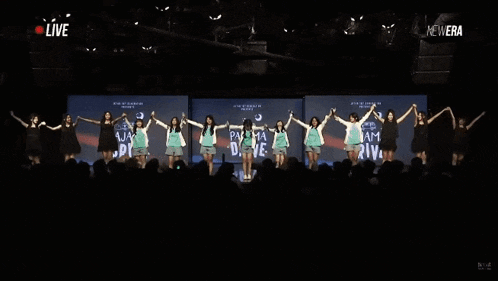 a group of girls are holding hands in front of a screen that says " live "