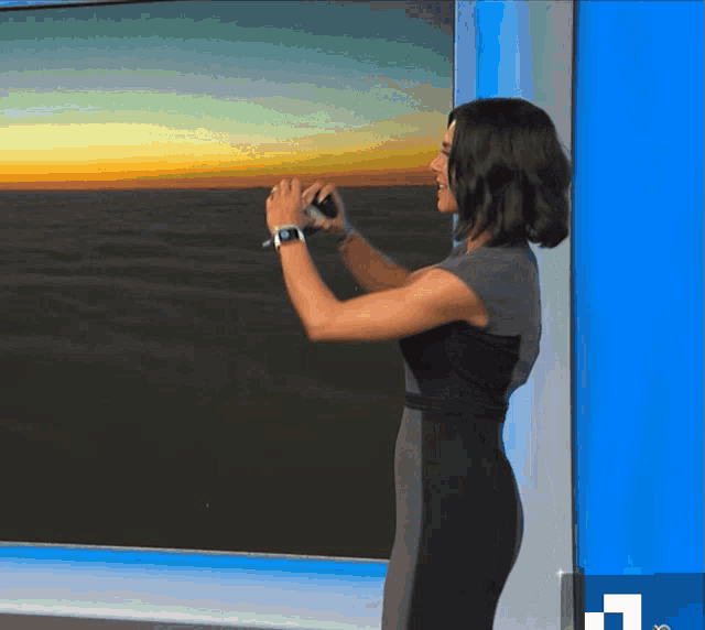 a woman is taking a picture of the ocean