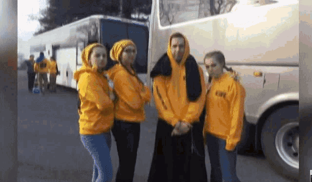 a group of people standing in front of a bus wearing yellow sweatshirts with the letters cvb on them