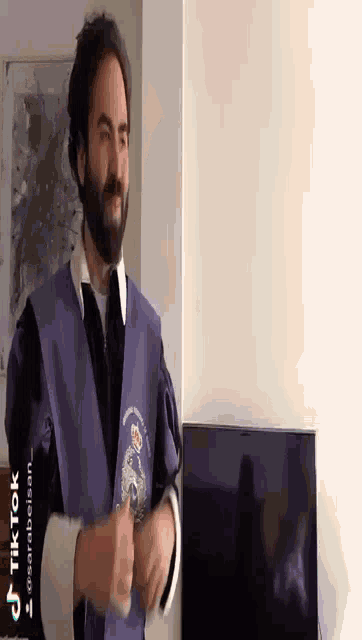 a man in a purple cape is standing in front of a tv with tiktok written at the bottom