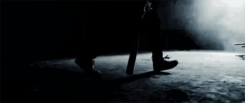 a person walking in the dark holding a sword