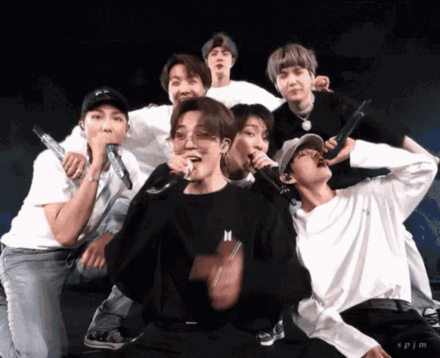 a group of young men are posing for a picture and one of them is wearing a black shirt with the letter m on it