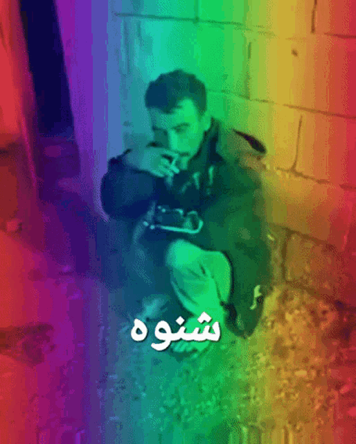 a man smoking a cigarette in front of a rainbow colored background with the word shoo on it