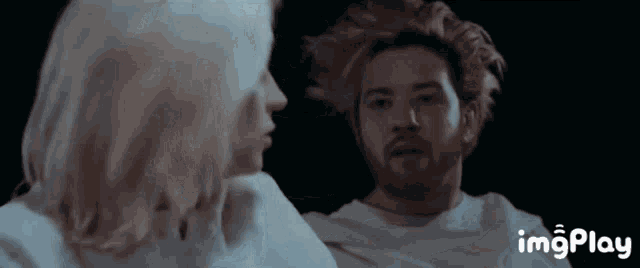 a man and a woman are looking at each other with imgplay written on the bottom right