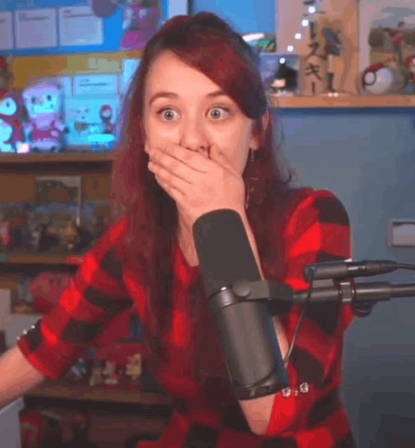 a woman with red hair is covering her mouth in front of a microphone