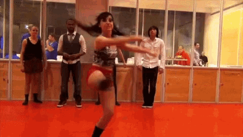 a group of people are dancing in a room with red floors