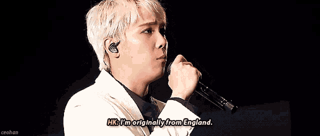 a man singing into a microphone with the words hk i 'm originally from england above him