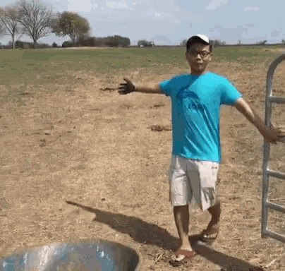 a man in a blue shirt is standing in a field with his arms outstretched ..