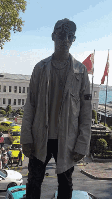 a man wearing sunglasses and a stone island jacket stands in front of a building