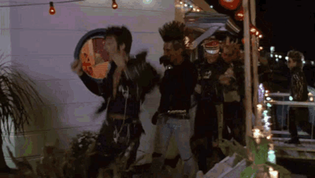 a group of punks are dancing in front of a building with christmas lights