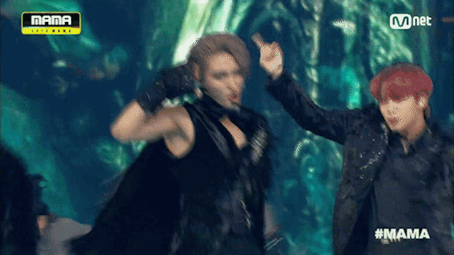 two men are dancing on a stage with the word mama on the top
