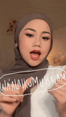 a woman wearing a hijab and a white shirt says wa alaikumussalam