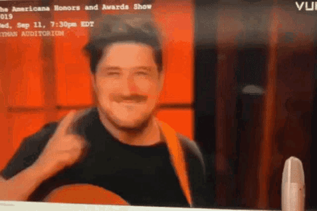 a man is giving a thumbs up while holding a guitar