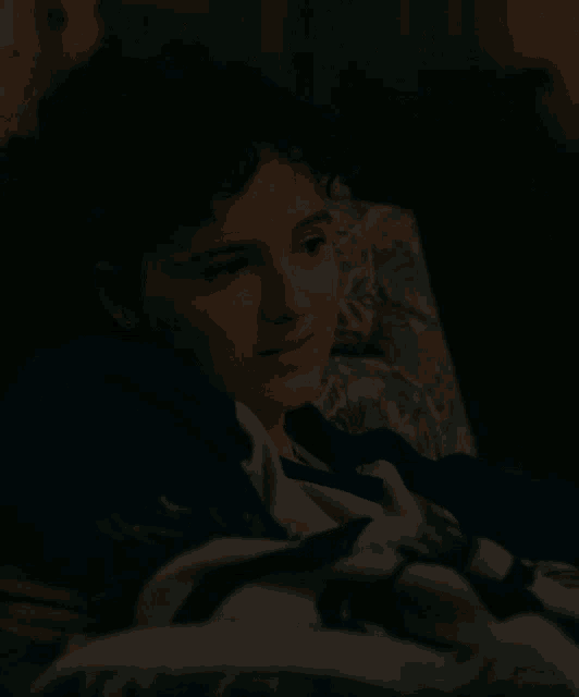 a young boy is laying on a bed with a blanket on