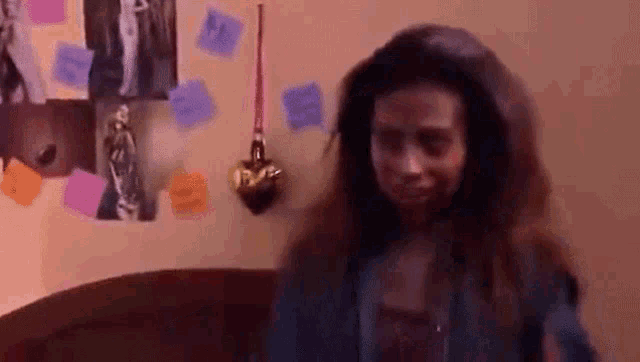 a woman with long hair is standing in front of a wall covered in sticky notes .