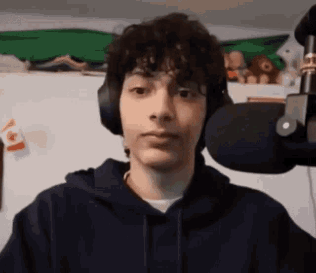 a young man with curly hair is wearing headphones and looking at the camera .