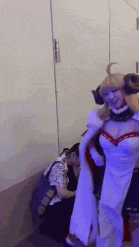 a woman in a costume is dancing in front of a man sitting on the floor