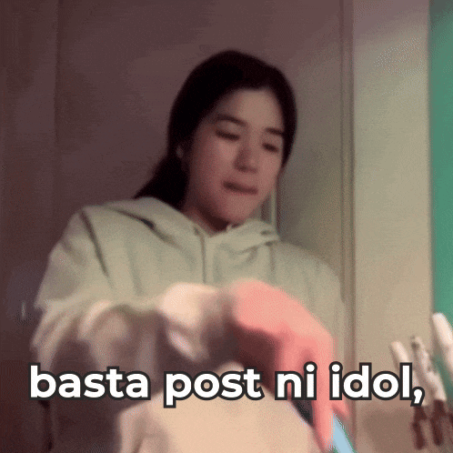 a woman in a green hoodie is holding a cell phone with the words basta post ni idol below her
