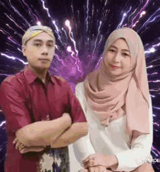 a man and a woman are standing next to each other with their arms crossed .