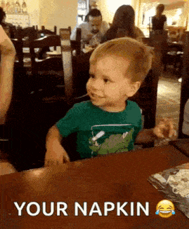 a little boy is sitting at a table with a napkin on it .