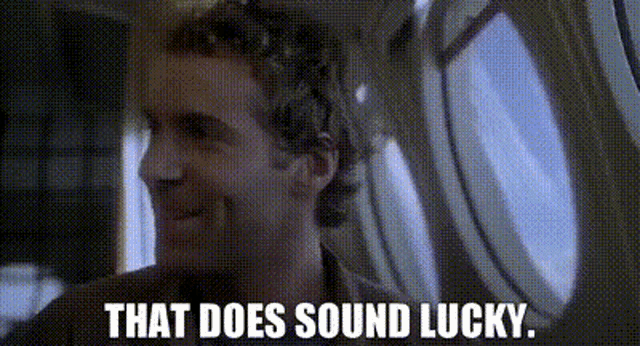 a man is smiling while sitting in an airplane and the words `` that does sound lucky '' are written above him .