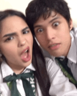 a boy and a girl are posing for a picture and the girl has her tongue hanging out