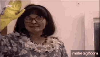 a woman wearing glasses and a flower necklace is wearing yellow gloves .