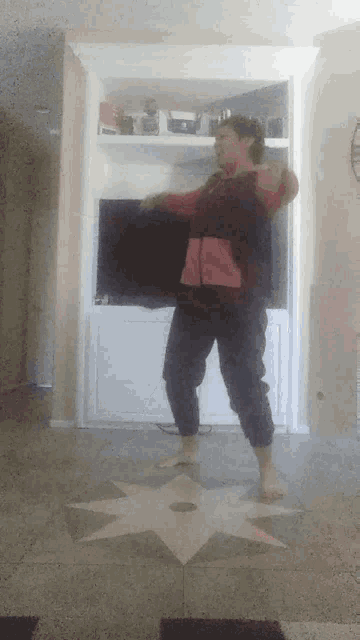 a woman in a red jacket is dancing in front of a flat screen tv