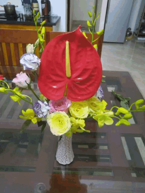 a vase filled with flowers has a red flower in the middle