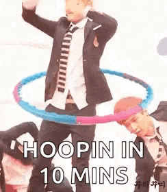 a man in a suit and tie is holding a hula hoop in his hands .