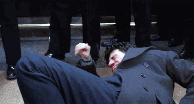 a man in a black coat is laying on the floor