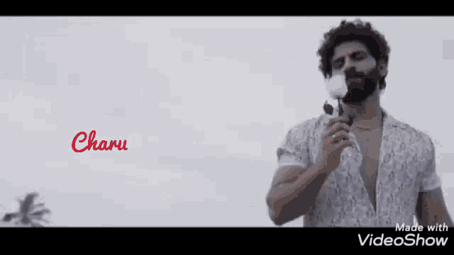 a man with a beard is holding a microphone in front of a white background with the word charu on it