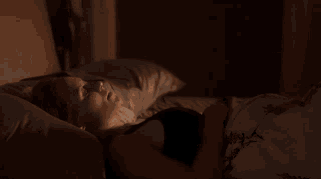 a woman is laying on a bed with her legs crossed and a black tank top on .