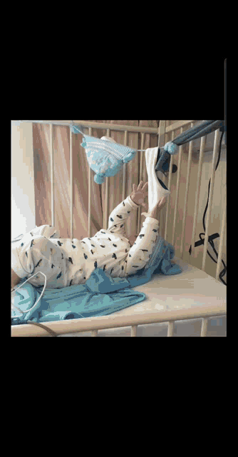 a baby is laying on his back in a crib holding a blanket