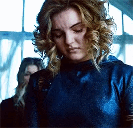 a woman with curly blonde hair is wearing a blue top