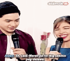 a man and a woman are talking into microphones and the woman is smiling .