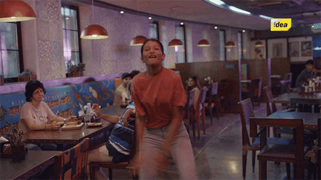 a woman is dancing in a restaurant with a sign that says idea on it
