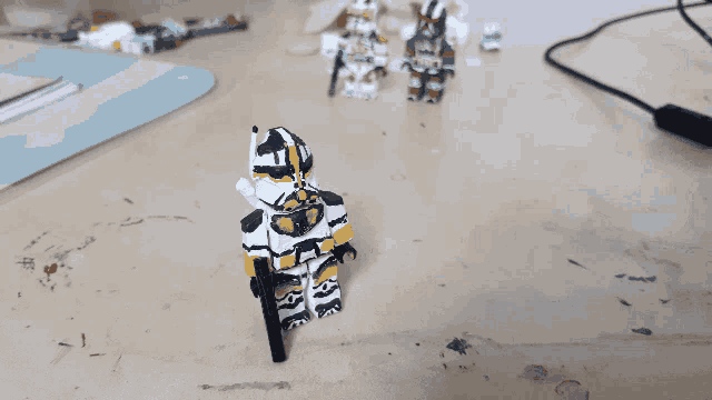 a black and white lego figure with a gun stands on a table